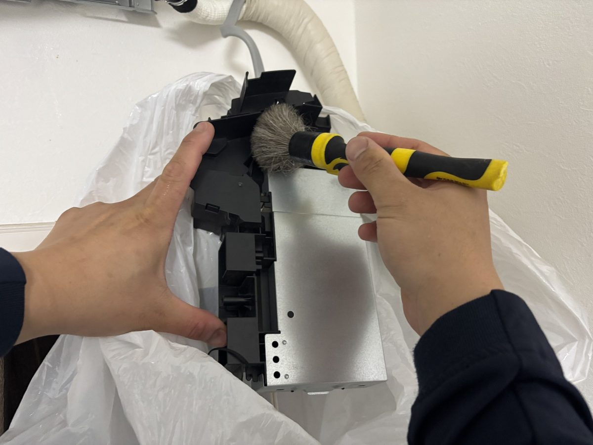 取り外した電装部品を刷毛でホコリ払いしているところ