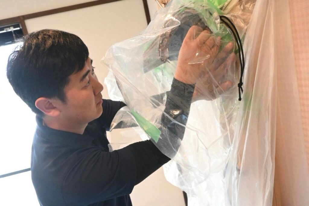 長畑が研修でエアコンを養生し、分解している様子の写真