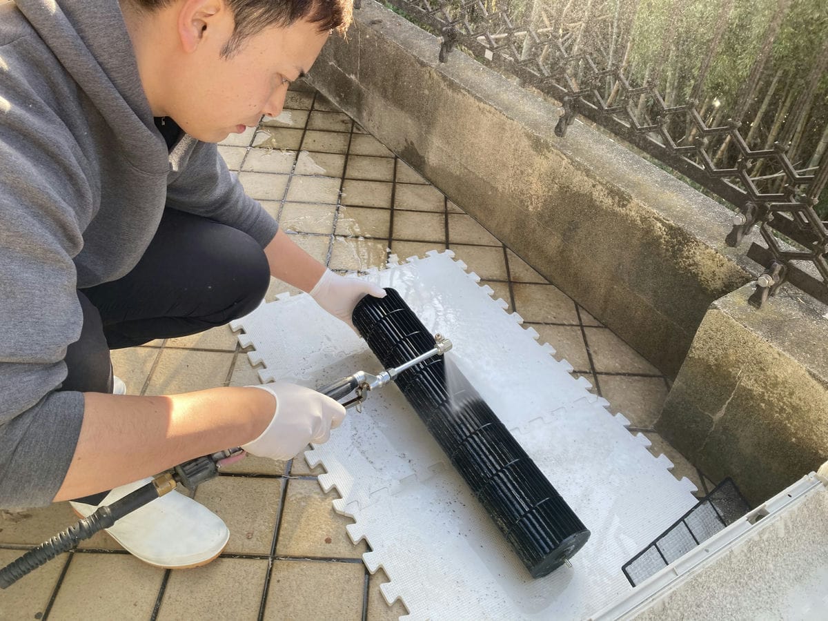 庭で送風ファンで高圧洗浄をしている作業員