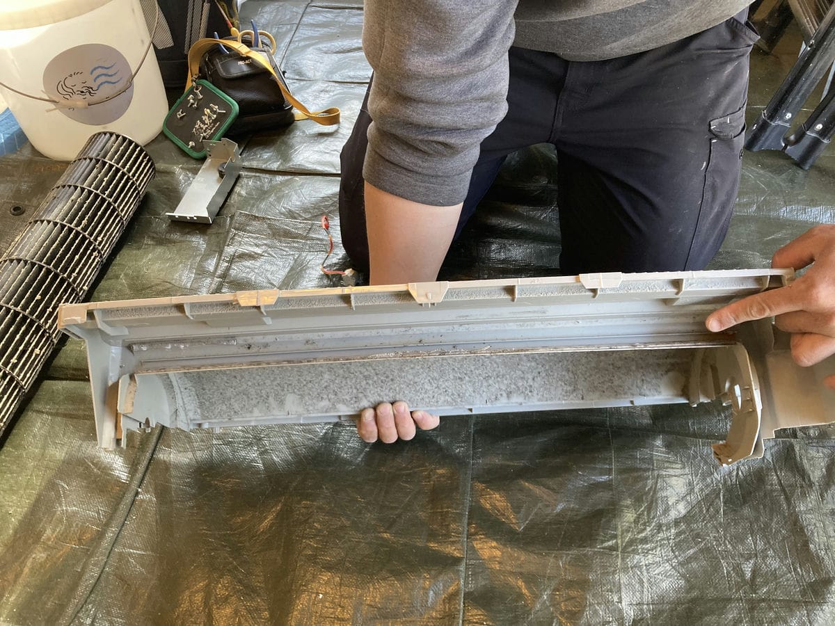 お客様にエアコンの内部を見せている作業員