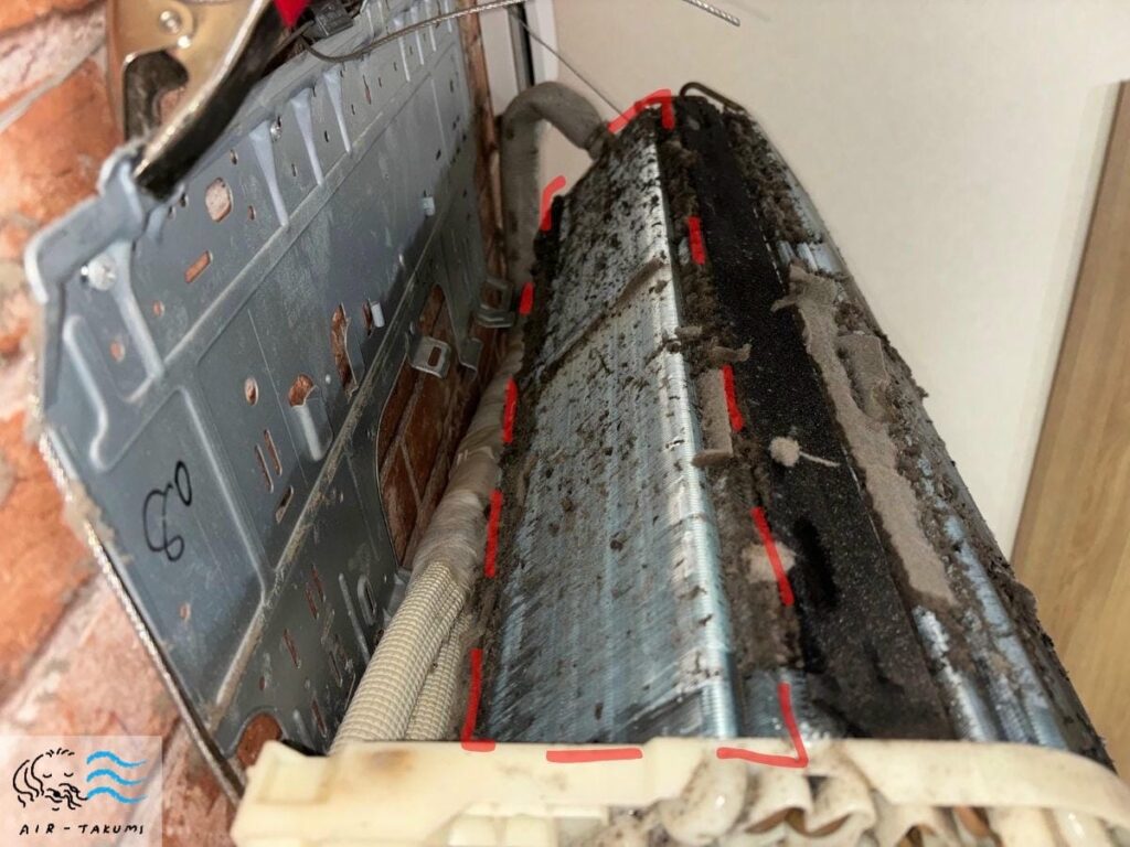 ダイキンエアコンの熱交換器裏側を分解撮影。フィン(アルミ板)の隙間全体に微細なホコリと黒カビが固着している様子