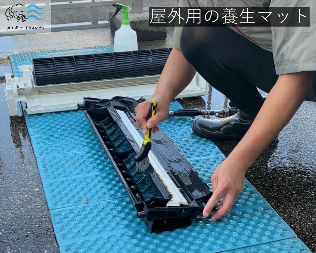 屋外用の養生マットでエアコンを洗浄している様子