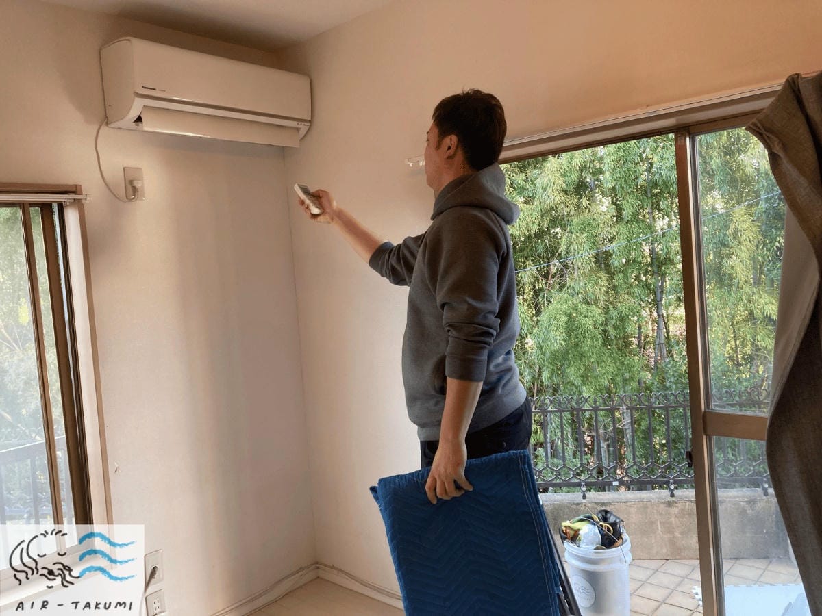 エアコンクリーニングの作業前に、リモコンで正常に動作するか試運転を行っている様子。