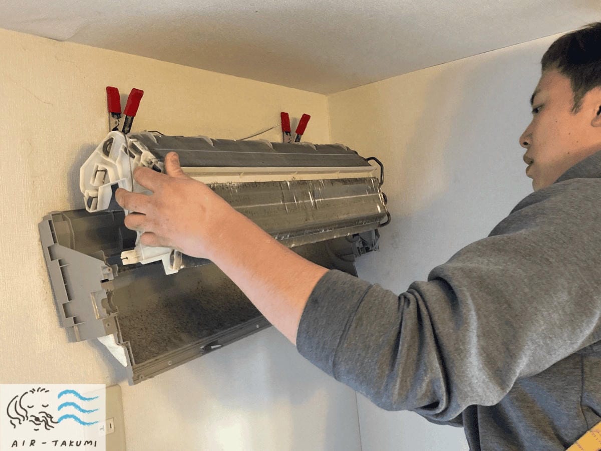 壁と熱交換器の間の汚れも見逃さないよう、エアコン本体を壁から浮かせる「背抜き」作業中。