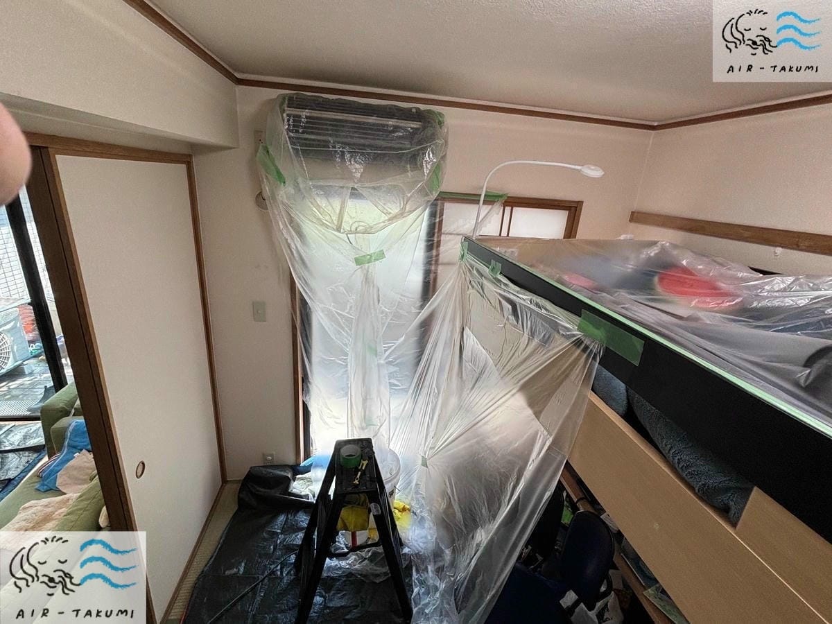 壁やエアコン周辺の家具を養生している様子